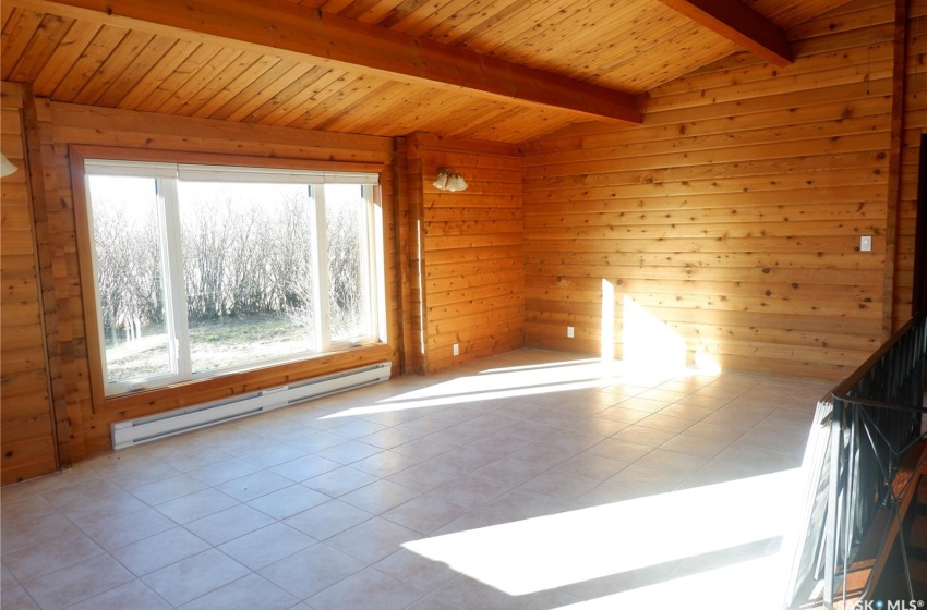 Spare room featuring lofted ceiling with beams, light tile patterned floors, wood walls, a baseboard radiator, and wooden ceiling