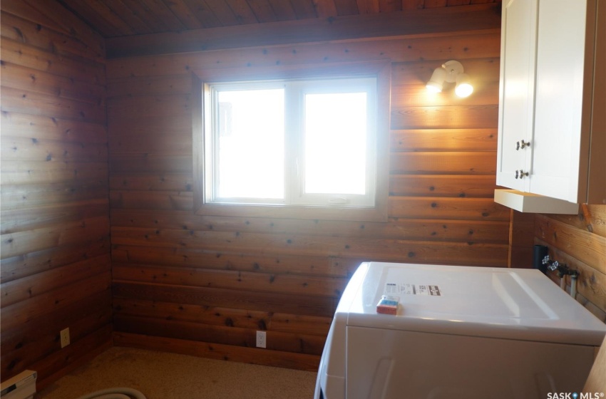 Clothes washing area featuring wooden walls, cabinets, washer / dryer, and wooden ceiling