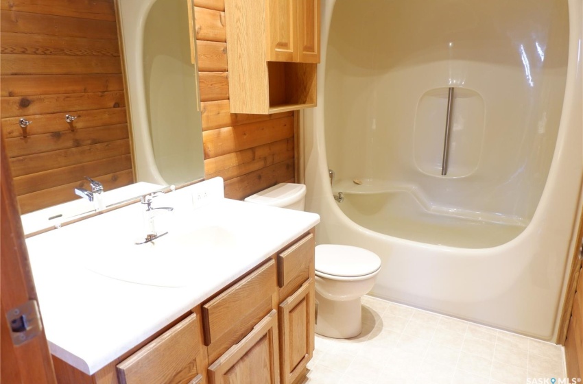 Bathroom featuring toilet, vanity, wooden walls, and a shower