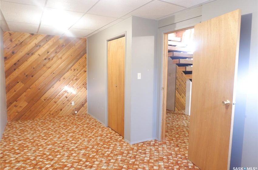 Hallway with a drop ceiling and wood walls