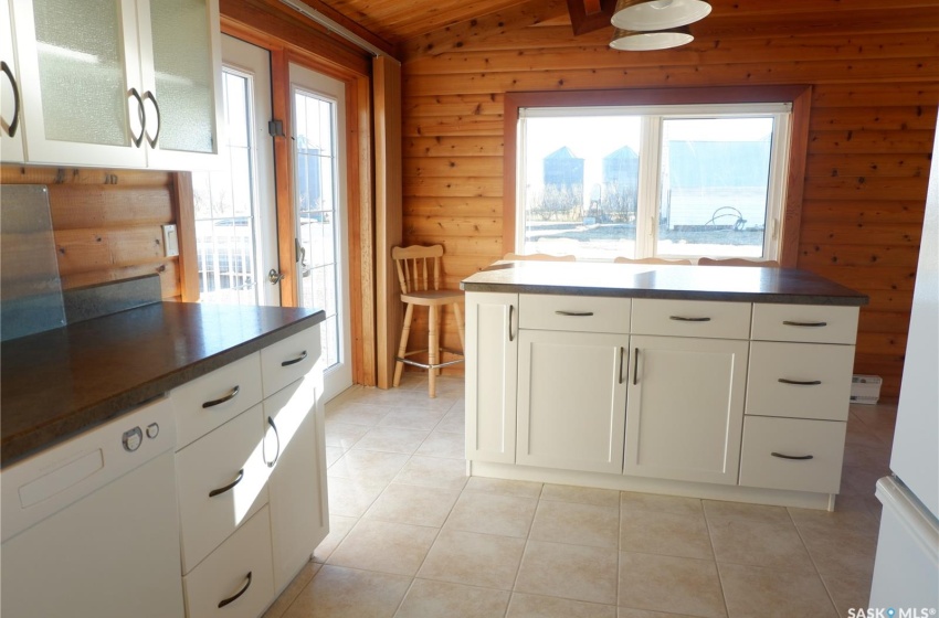 Kitchen featuring white cabinets, light tile patterned flooring, plenty of natural light, and lofted ceiling