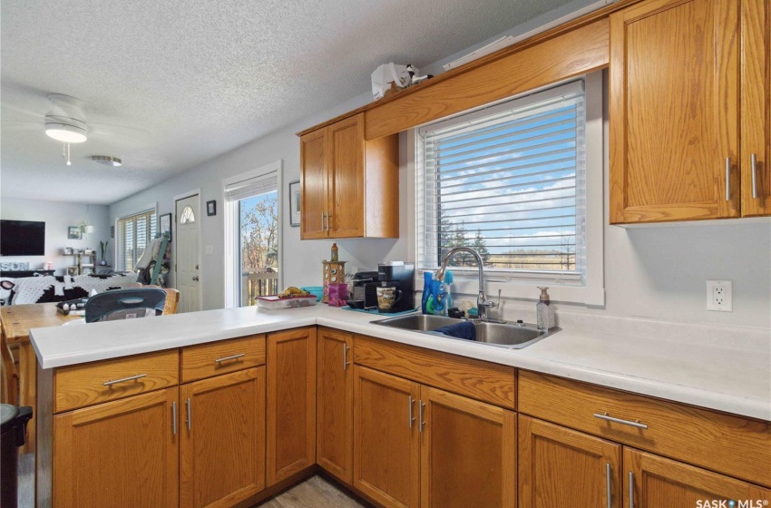 Kitchen with ceiling fan, a textured ceiling, sink, and kitchen peninsula