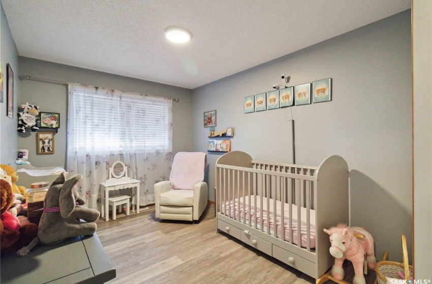 Bedroom featuring vinyl plank flooring, a nursery area, and a textured ceiling