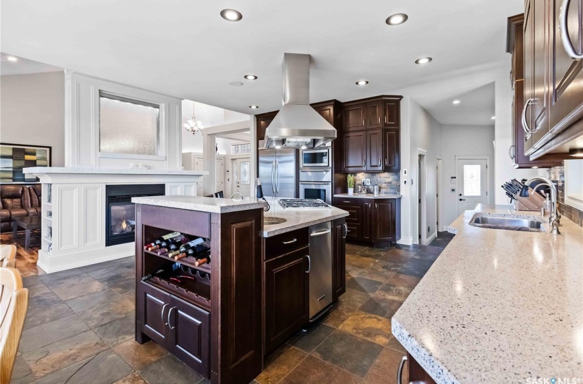 Kitchen with sink, range hood, decorative light fixtures, a kitchen island, and stainless steel appliances