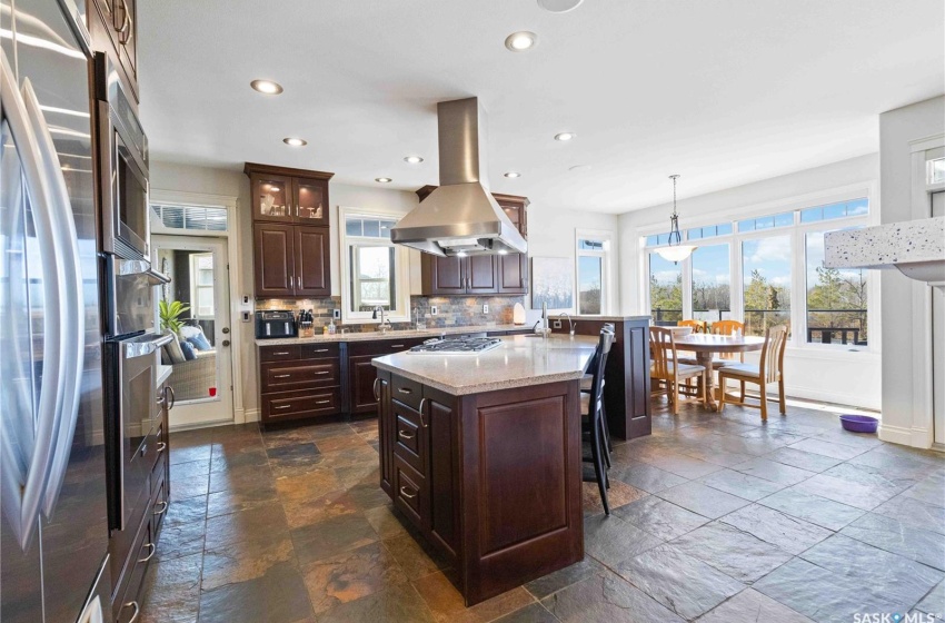 Kitchen featuring decorative light fixtures, island range hood, tasteful backsplash, and a healthy amount of sunlight