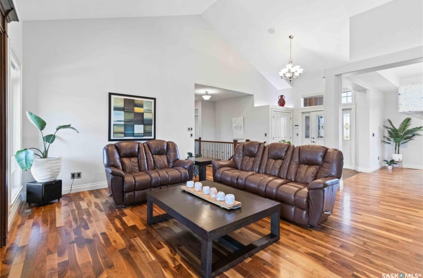 Living room with hardwood / wood-style flooring, a notable chandelier, and high vaulted ceiling