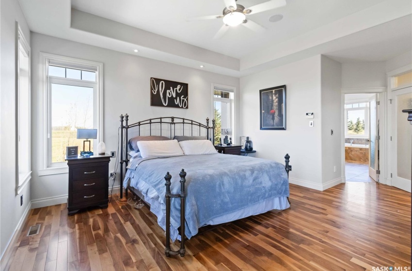 Bedroom featuring ensuite bath, multiple windows, dark wood-type flooring, and ceiling fan