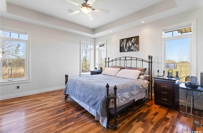 Bedroom featuring a raised ceiling, ceiling fan, and dark wood-type flooring