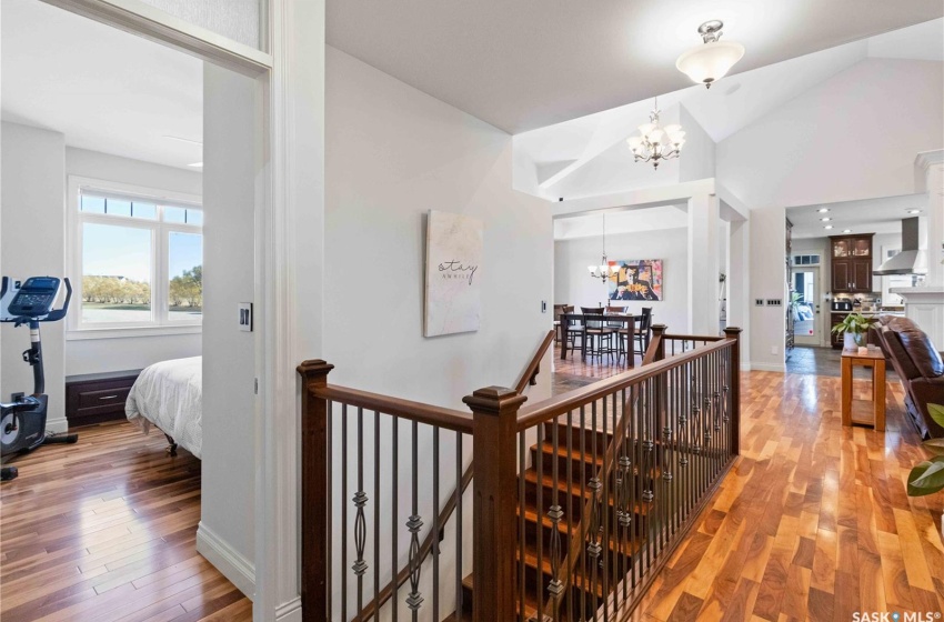 Corridor with hardwood / wood-style flooring, high vaulted ceiling, and an inviting chandelier