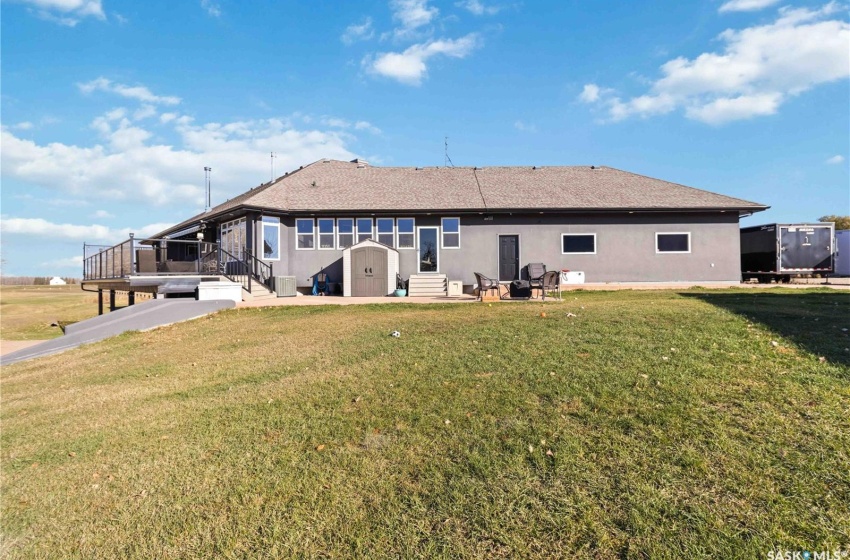 Back of house featuring a lawn, cooling unit, a storage shed, and a wooden deck