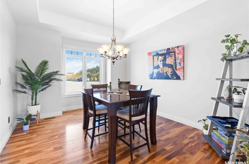 Dining room featuring a raised ceiling, hardwood / wood-style floors, and a chandelier