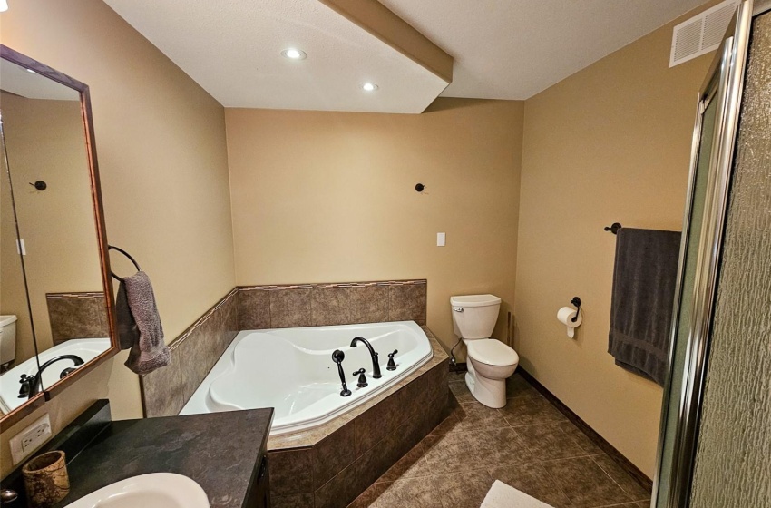 Bathroom with tile patterned floors, vanity, toilet, and tiled tub