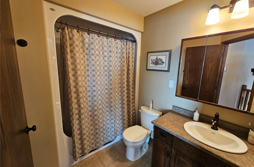 Bathroom with vanity, toilet, tile patterned floors, a textured ceiling, and a shower with shower curtain