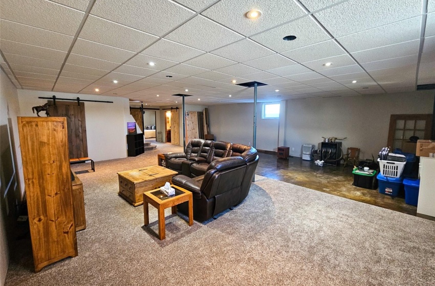 Carpeted living room with a barn door and a paneled ceiling