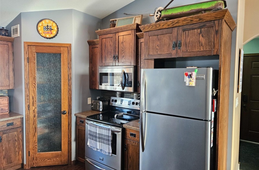 Kitchen featuring vaulted ceiling, appliances with stainless steel finishes, and dark hardwood / wood-style floors