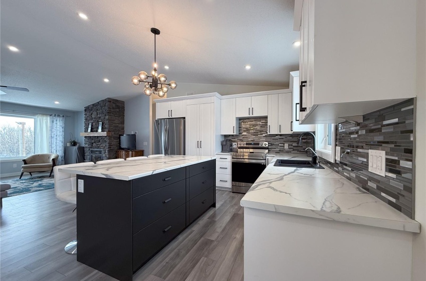 Kitchen with a kitchen island, appliances with stainless steel finishes, sink, white cabinets, and hanging light fixtures