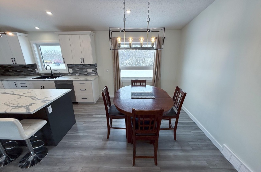 Dining room featuring dark hardwood / wood-style flooring, sink, a textured ceiling, and an inviting chandelier