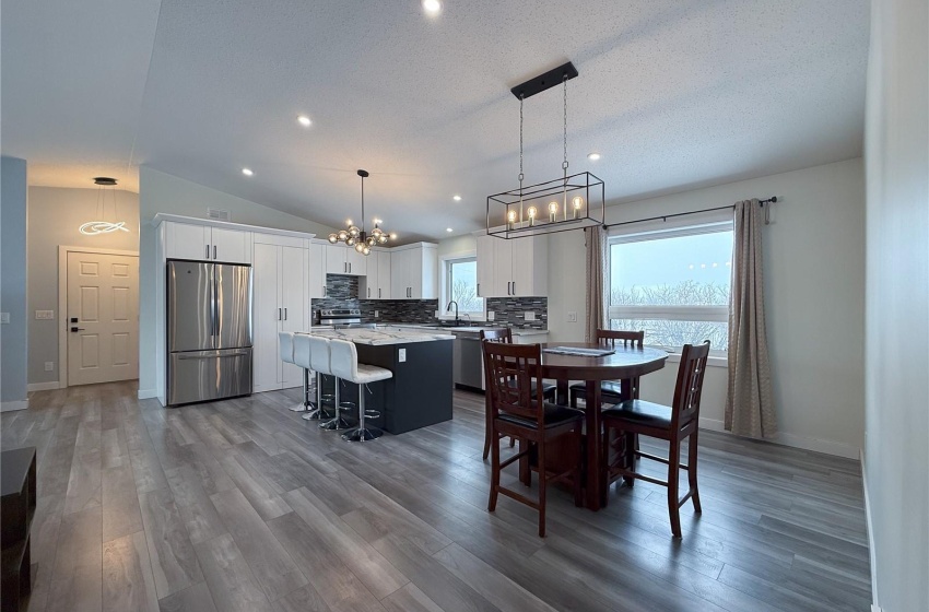 Dining space featuring lofted ceiling, sink, wood-type flooring, and a textured ceiling