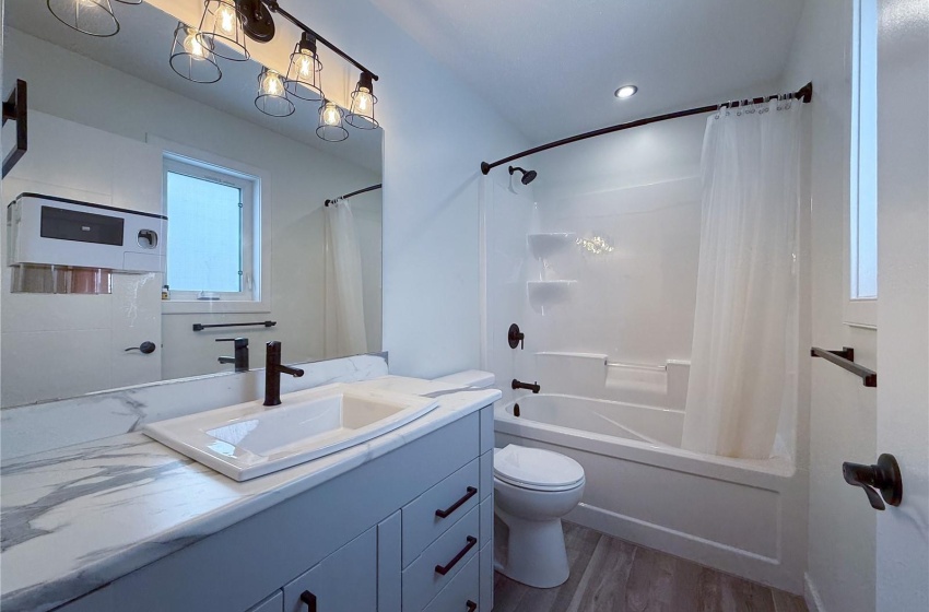 Full bathroom featuring vanity, hardwood / wood-style flooring, shower / bath combination with curtain, and toilet