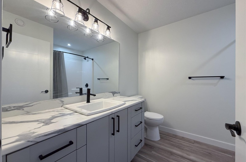 Bathroom featuring hardwood / wood-style floors, a shower with shower curtain, vanity, a textured ceiling, and toilet