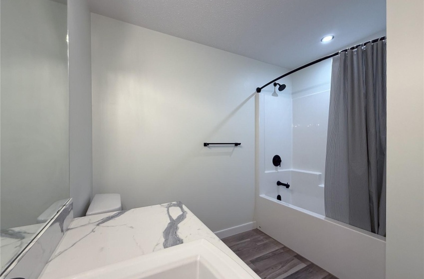 Bathroom featuring hardwood / wood-style flooring, toilet, and shower / bath combo with shower curtain