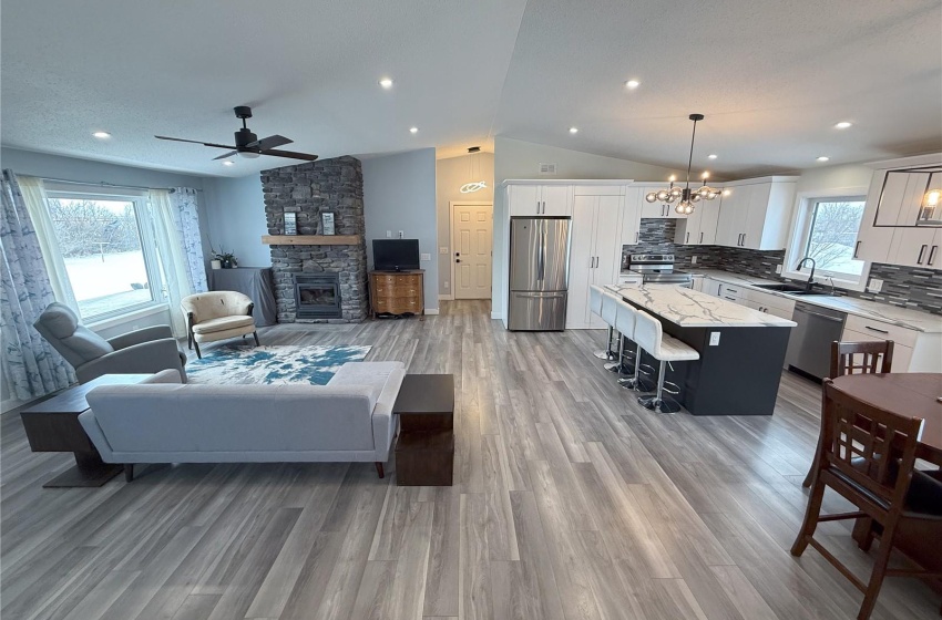 Living room with sink, a fireplace, light hardwood / wood-style floors, ceiling fan with notable chandelier, and vaulted ceiling