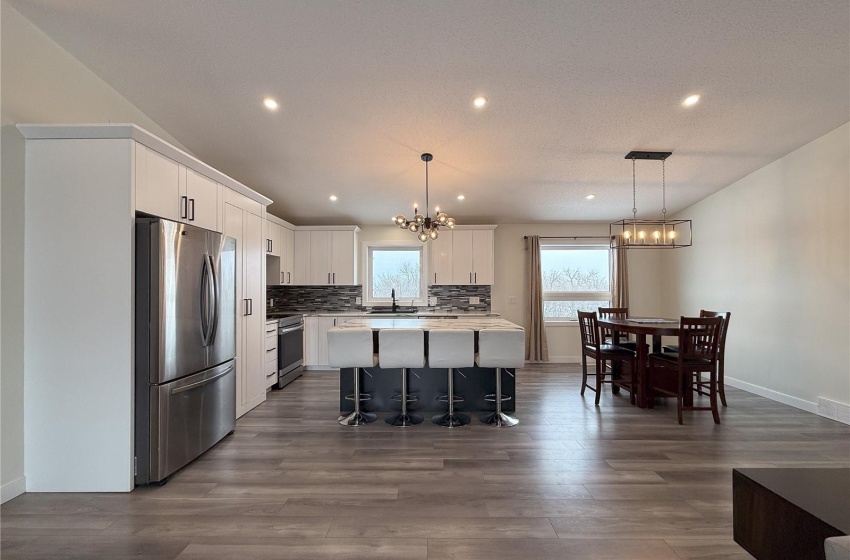 Kitchen with decorative light fixtures, a chandelier, appliances with stainless steel finishes, a kitchen island, and white cabinets