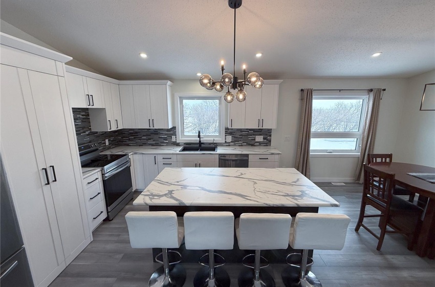 Kitchen featuring sink, white cabinetry, a center island, appliances with stainless steel finishes, and pendant lighting