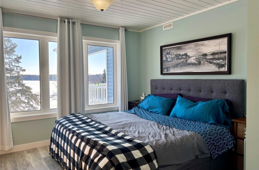 Bedroom featuring a water view, wood-type flooring, crown molding, and multiple windows