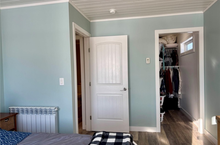 Bedroom featuring crown molding, a walk in closet, dark hardwood / wood-style flooring, and radiator