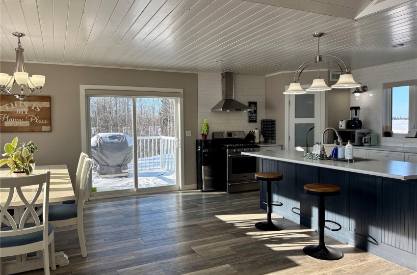 Kitchen with pendant lighting, dark hardwood / wood-style floors, stainless steel range with gas stovetop, and wall chimney range hood