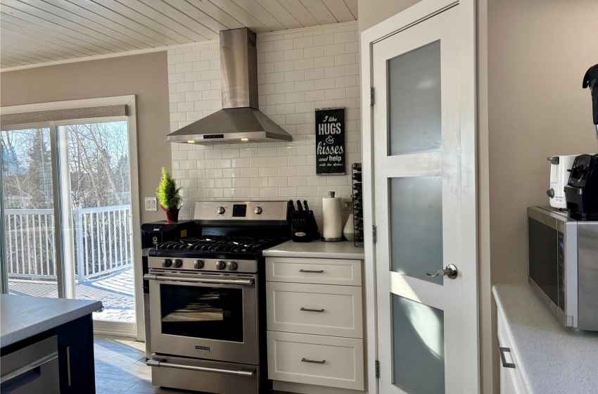 Kitchen featuring wall chimney range hood, stainless steel appliances, dark hardwood / wood-style floors, white cabinets, and decorative backsplash