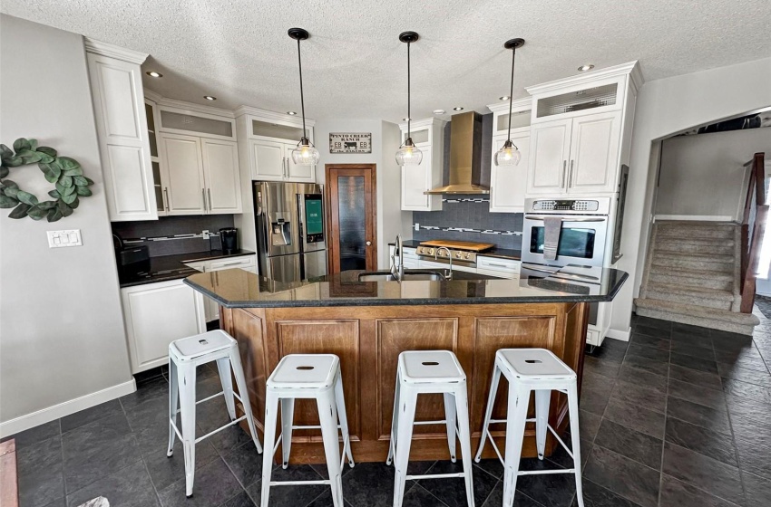 The kitchen boasts modern white cabinetry with a contrasting wood sit up tiered island. Sleek stainless steel appliances including a 6 burner Electrolux gas cooktop, double built in Frigidaire oven, state of the art computerized Samsung refrigerator, hood fan and lower microwave. rich granite countertops, ceramic tile backsplash and a corner walk-in pantry-a dream kitchen made for family and entertaining!