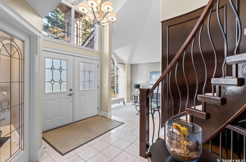 Foyer entrance with a wealth of natural light, an inviting chandelier, light tile patterned flooring, and high vaulted ceiling