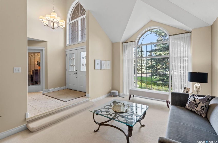 Carpeted family room featuring lofted ceiling and an inviting chandelier