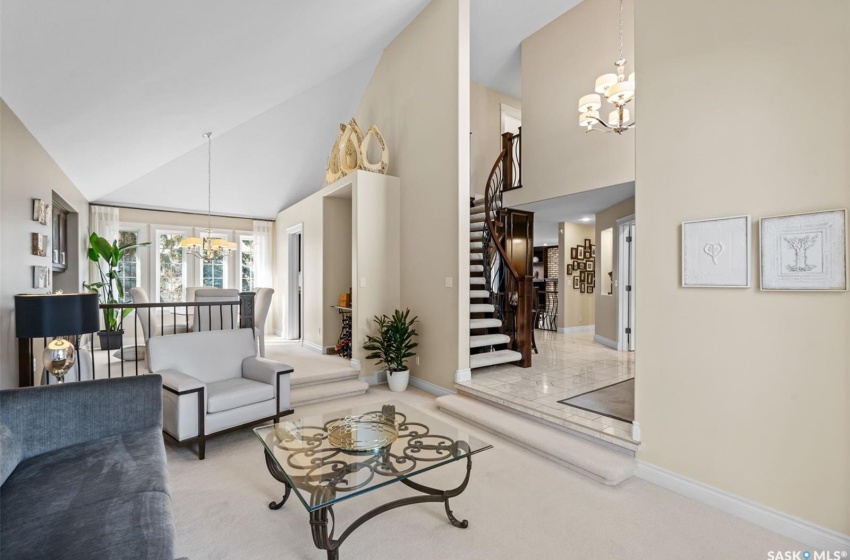 Carpeted family room featuring a notable chandelier and high vaulted ceiling