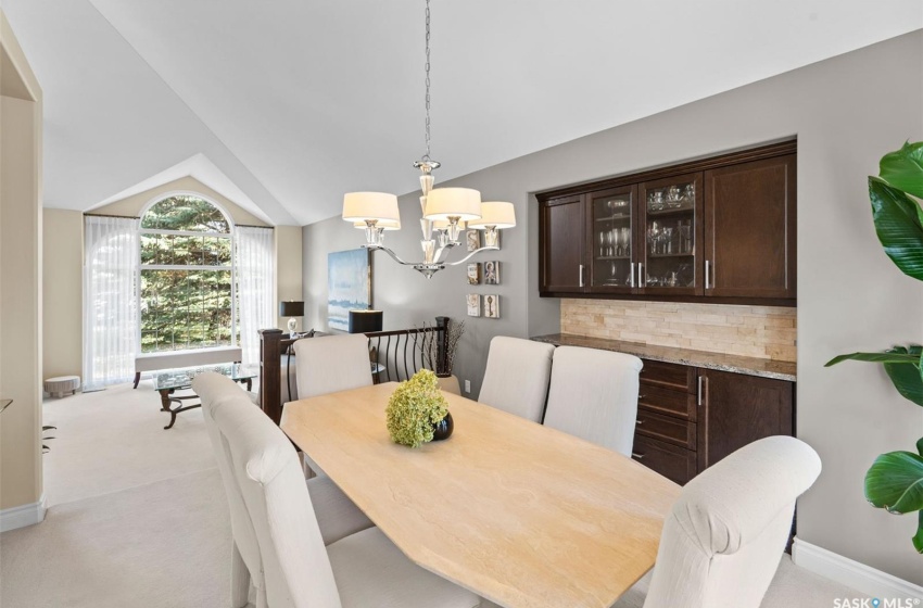 Carpeted dining space with lofted ceiling and a chandelier