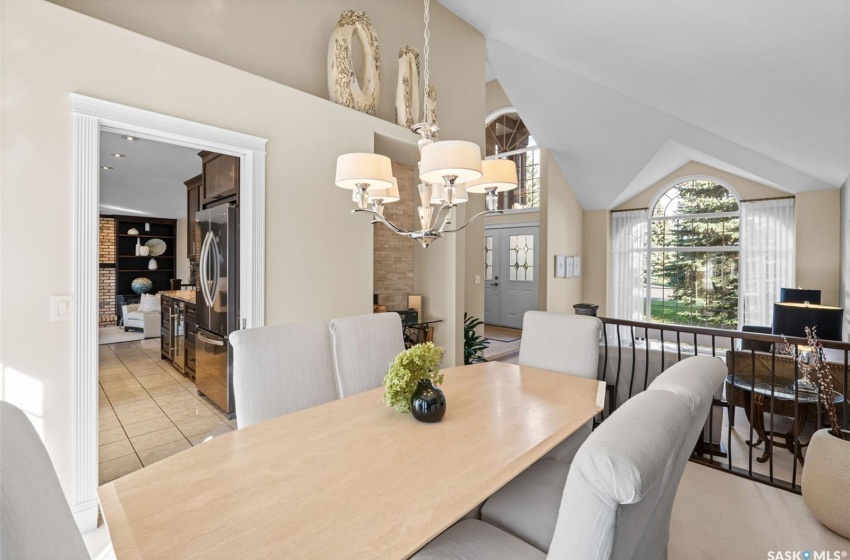 Tiled dining room featuring vaulted ceiling and an inviting chandelier