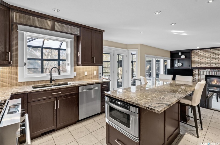 Kitchen featuring a kitchen island, a breakfast bar area, a brick fireplace, sink, and stainless steel appliances