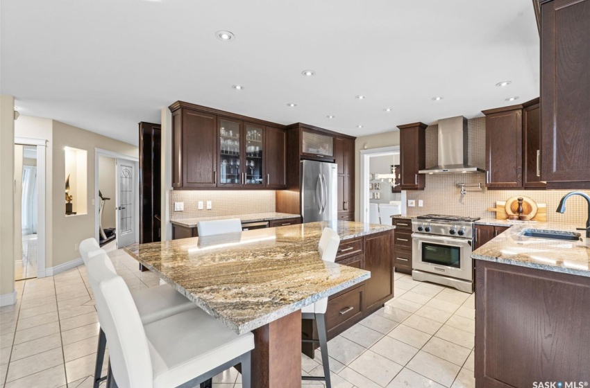 Kitchen featuring a kitchen island, a breakfast bar area, sink, wall chimney exhaust hood, and stainless steel appliances