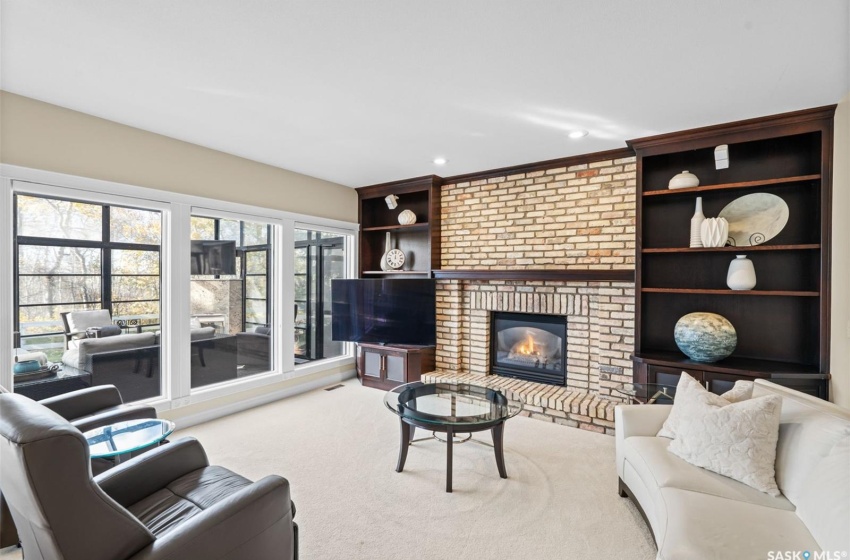 Carpeted living room with ornamental molding, a fireplace, and built in shelves