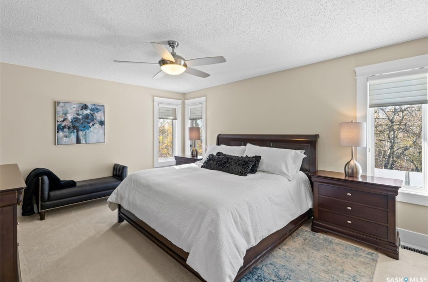 Bedroom with ceiling fan, light carpet, a textured ceiling, and multiple windows