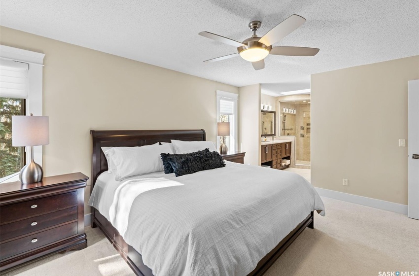 Bedroom with multiple windows, a textured ceiling, connected bathroom, and ceiling fan