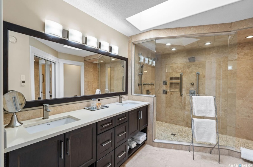 Bathroom with vanity, a textured ceiling, walk in shower, and a skylight