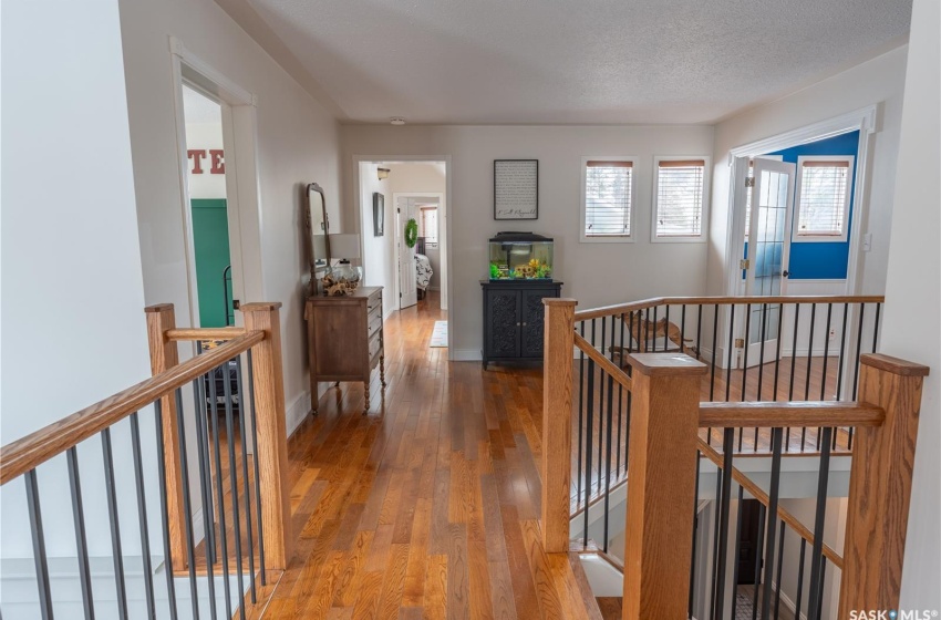 Hall with baseboards, a textured ceiling, an upstairs landing, and wood finished floors