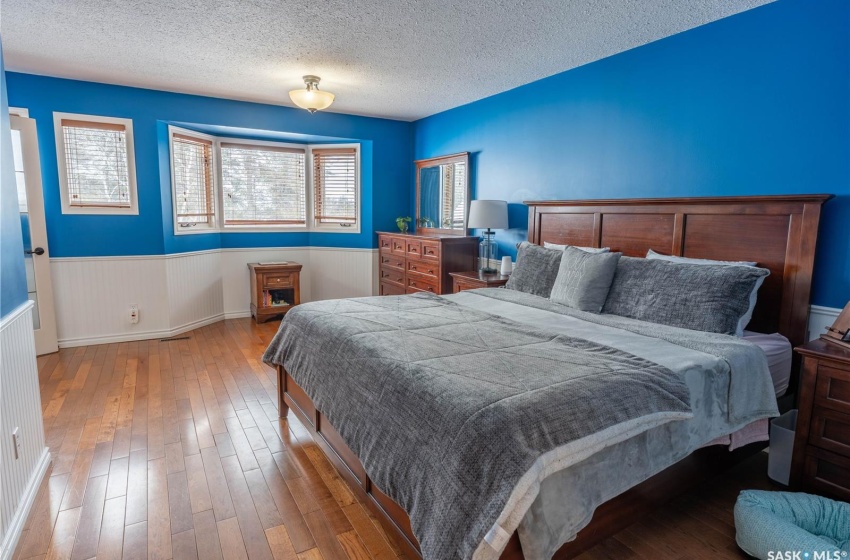 Bedroom with a wainscoted wall, a textured ceiling, and wood finished floors