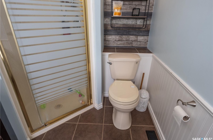 Bathroom with visible vents, toilet, a wainscoted wall, tile patterned flooring, and an enclosed shower