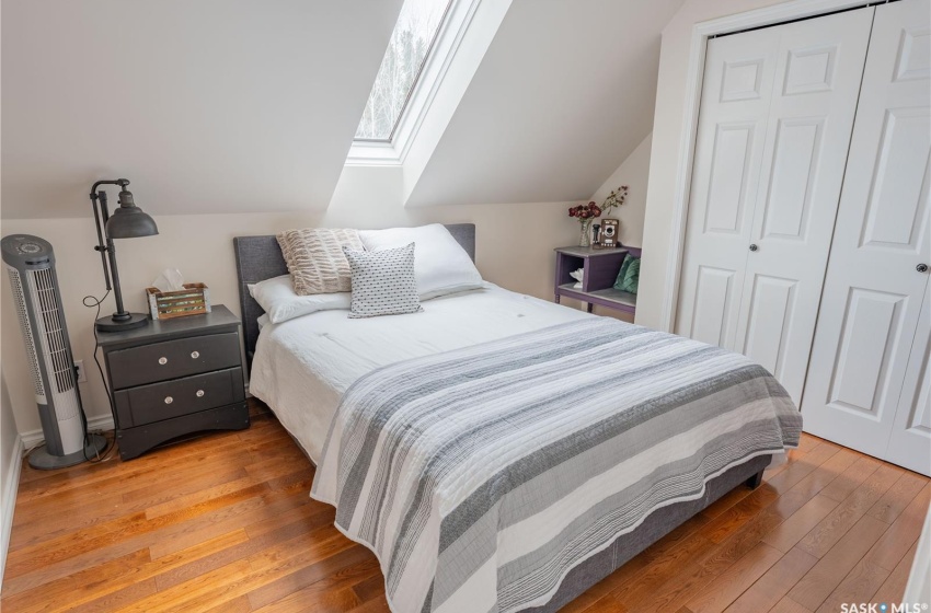 Bedroom with vaulted ceiling with skylight, a closet, and wood finished floors