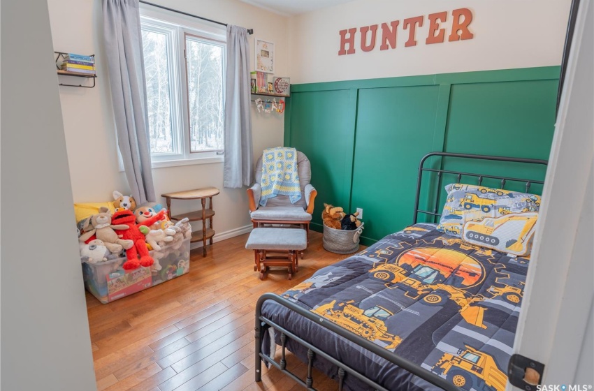 Bedroom featuring wood finished floors and a decorative wall