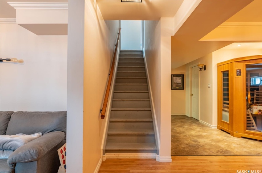 Stairway featuring baseboards, wood finished floors, and crown molding